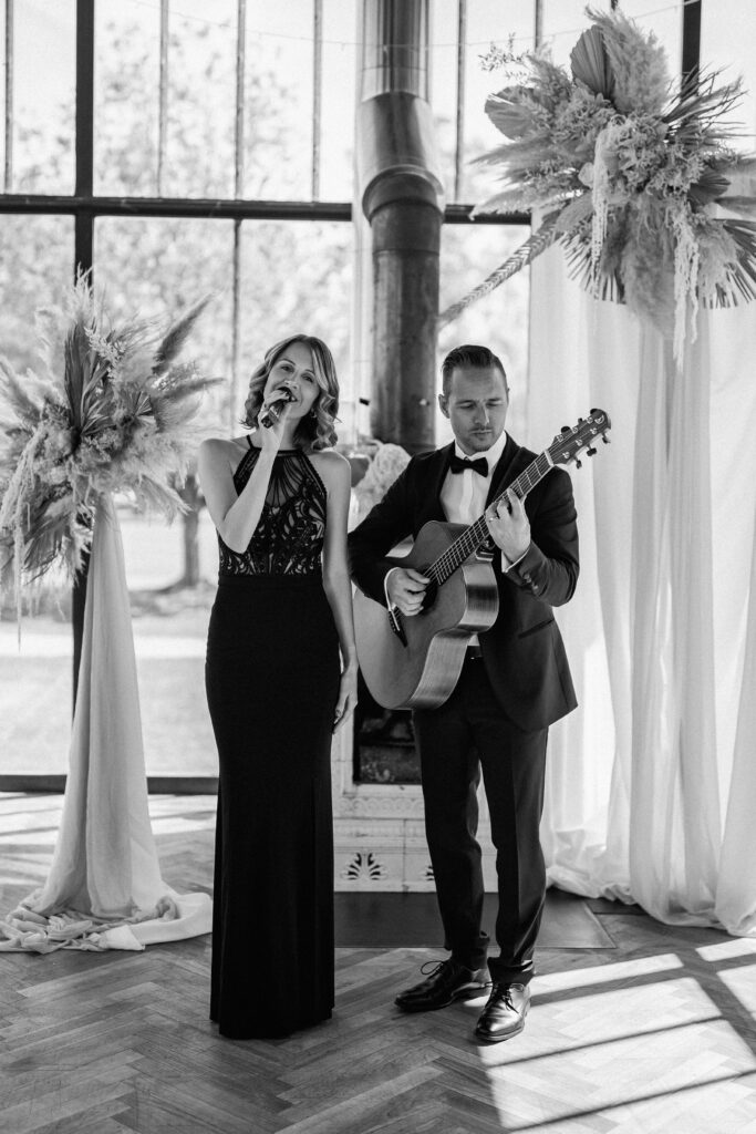 Eine Frau singt, während ihr Mann bei einer Hochzeit Gitarre spielt. 